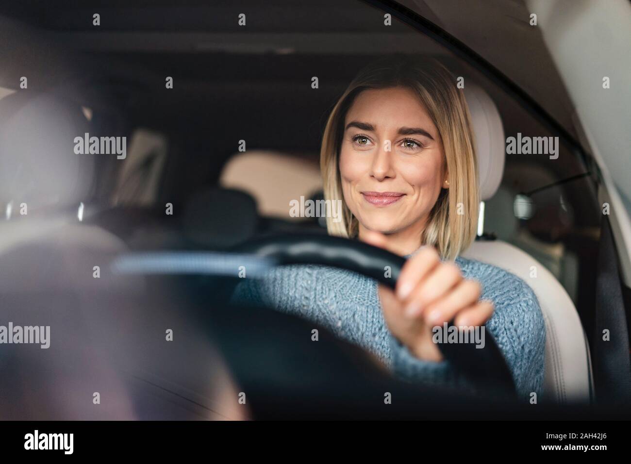 Ritratto di sorridente giovane donna alla guida di una vettura Foto Stock