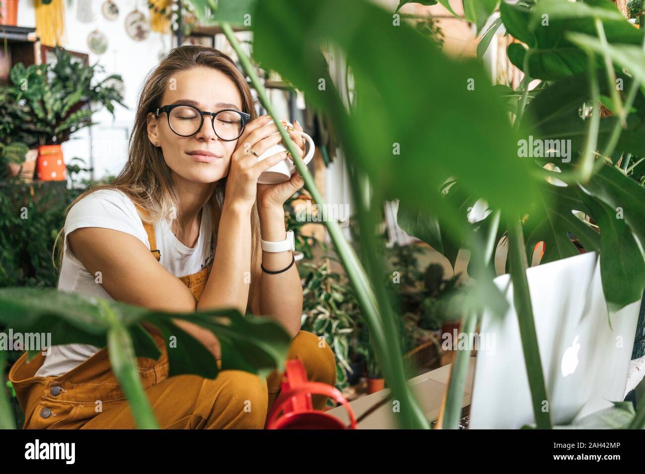 Giovane donna avente una pausa caffè in un piccolo negozio di giardinaggio Foto Stock