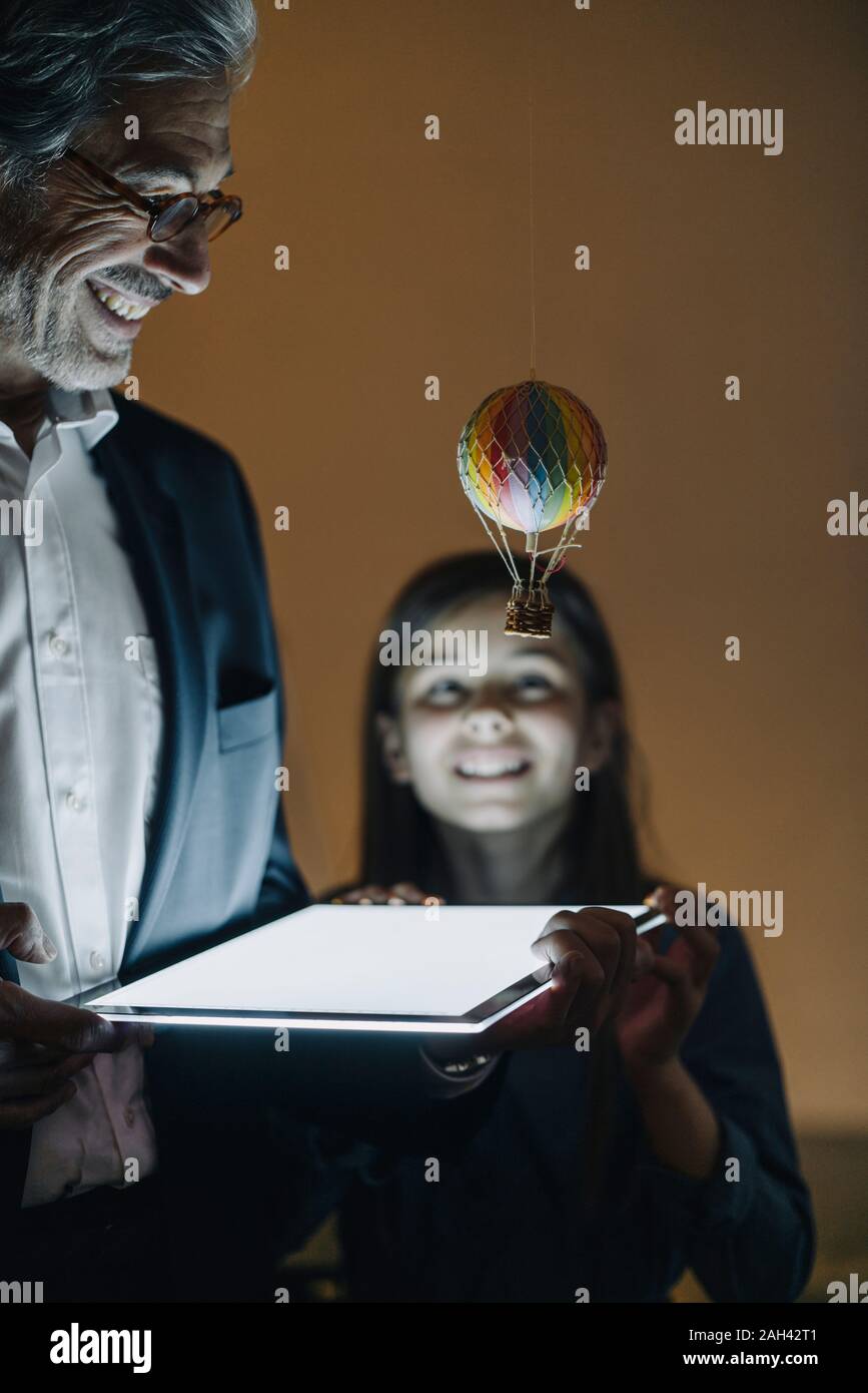 Felice buisinessman senior e la ragazza con mongolfiera e splendente tablet in ufficio Foto Stock