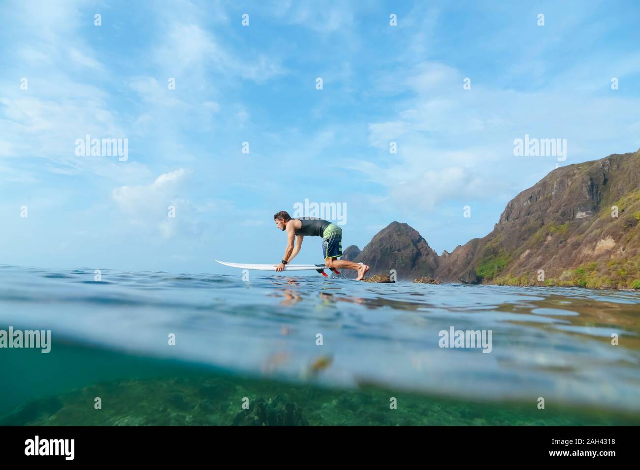 Surfer saltando dalla pietra, isola di Sumbawa, Indonesia Foto Stock