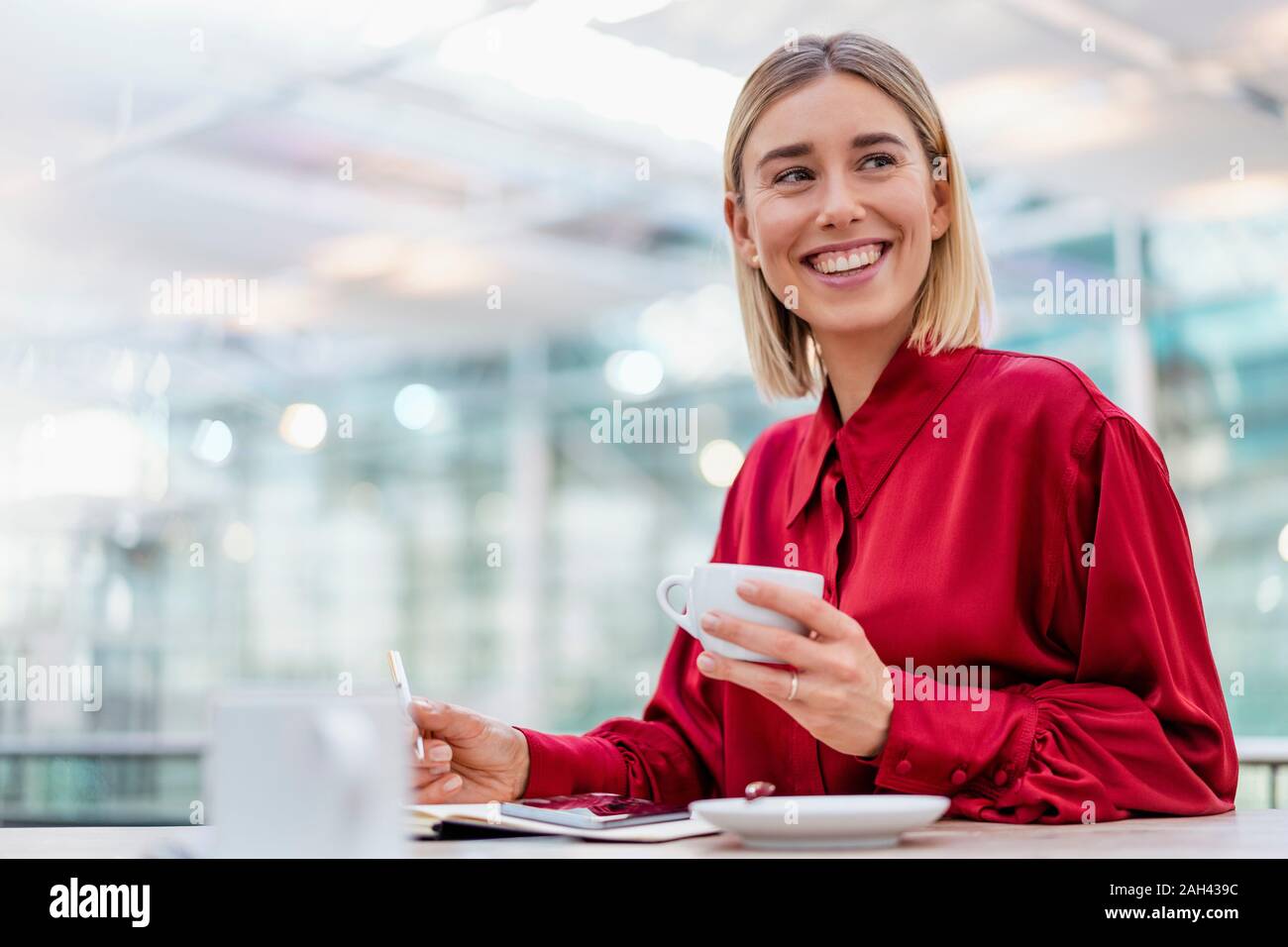 Felice giovane imprenditrice prendendo appunti in un cafe Foto Stock