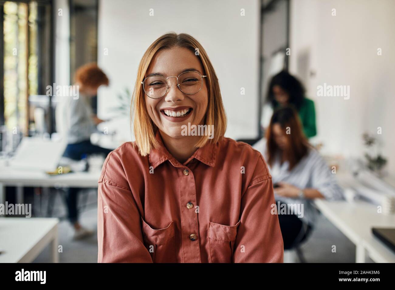 Ritratto di un felice imprenditrice in ufficio con i colleghi in background Foto Stock