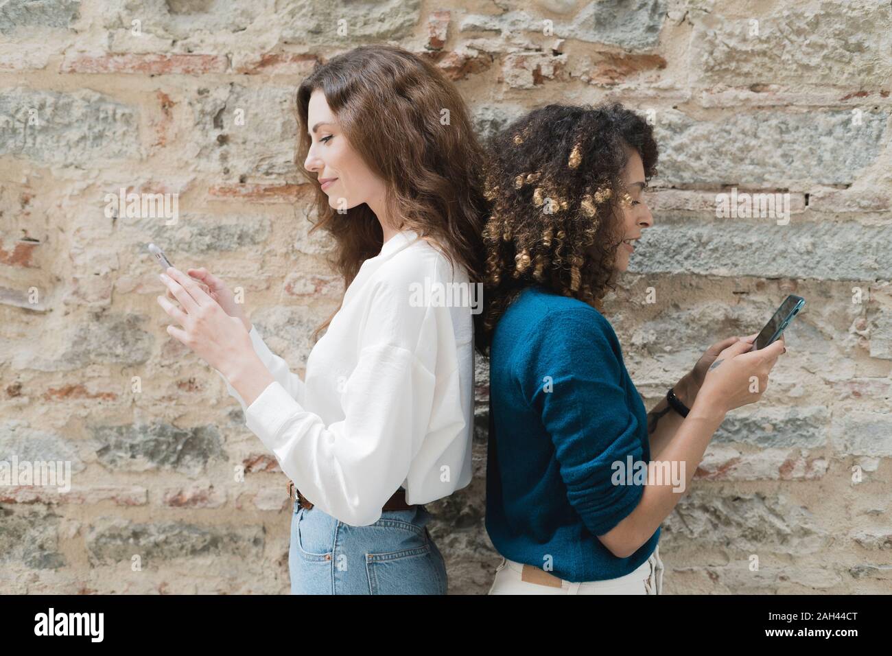 Due donne in piedi di schiena utilizzando gli smartphone Foto Stock