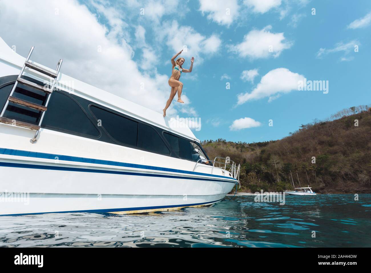 Donna che salta da yacht, Nusa Penida Island, Bali, Indonesia Foto Stock