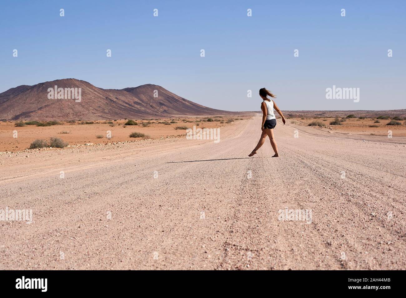 Donna che cammina nel mezzo di una strada sterrata, Damaraland, Namibia Foto Stock