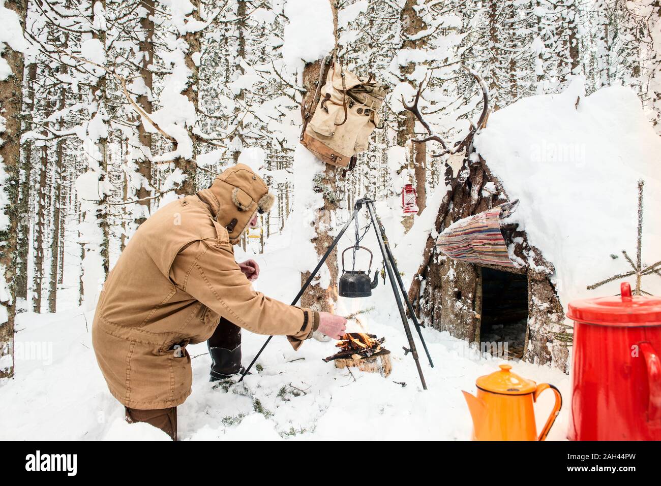 L'uomo preparando il tè in inverno foresta accanto a un rifugio in legno, Stato di Salisburgo, Austria Foto Stock