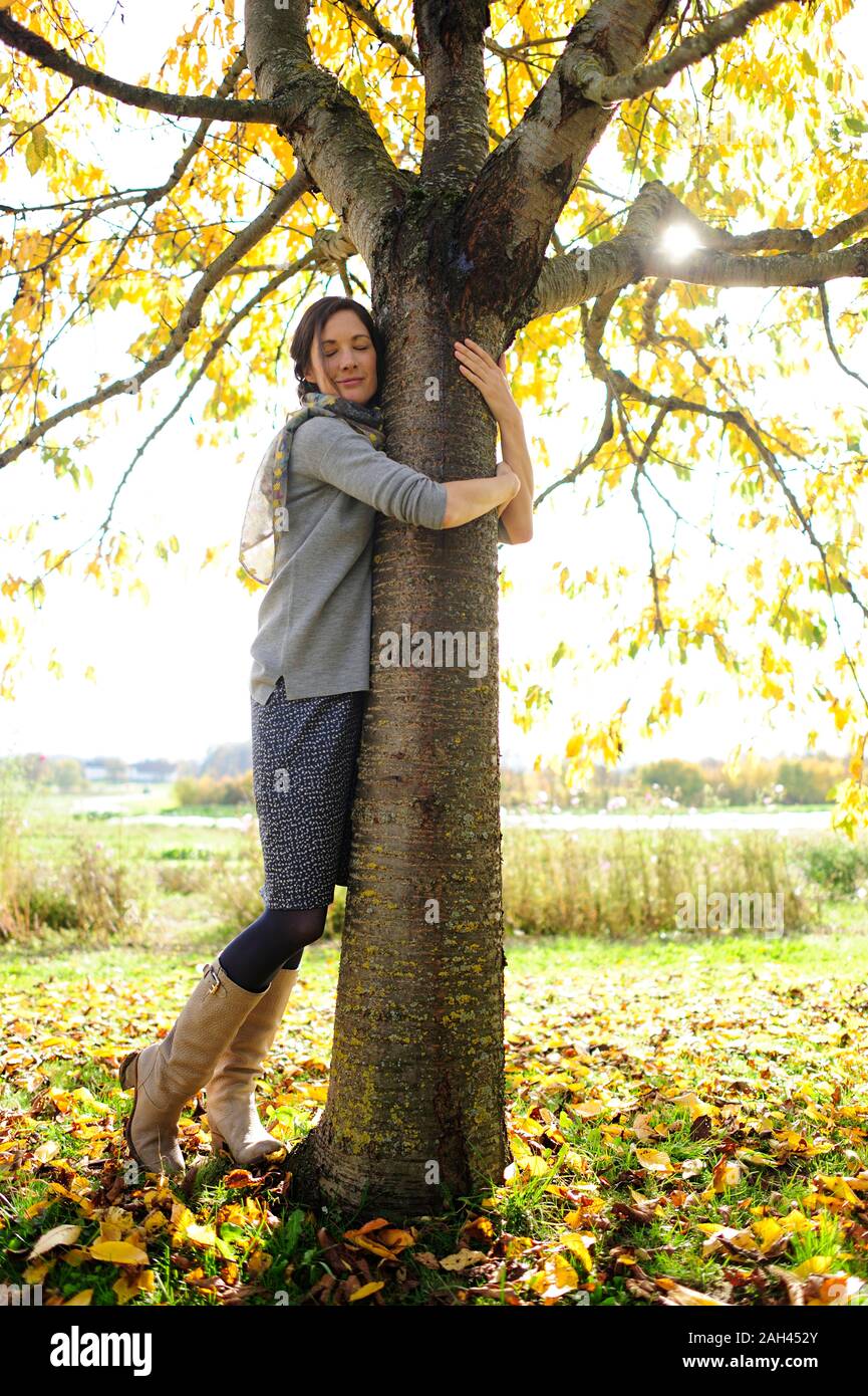 Donna abbracciando ad albero Foto Stock