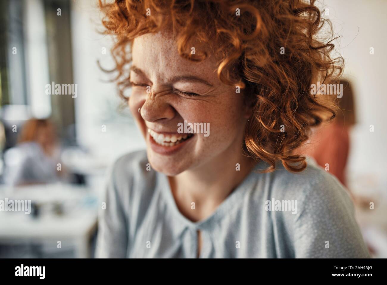 Ritratto di un ridere imprenditrice con gli occhi chiusi in ufficio Foto Stock