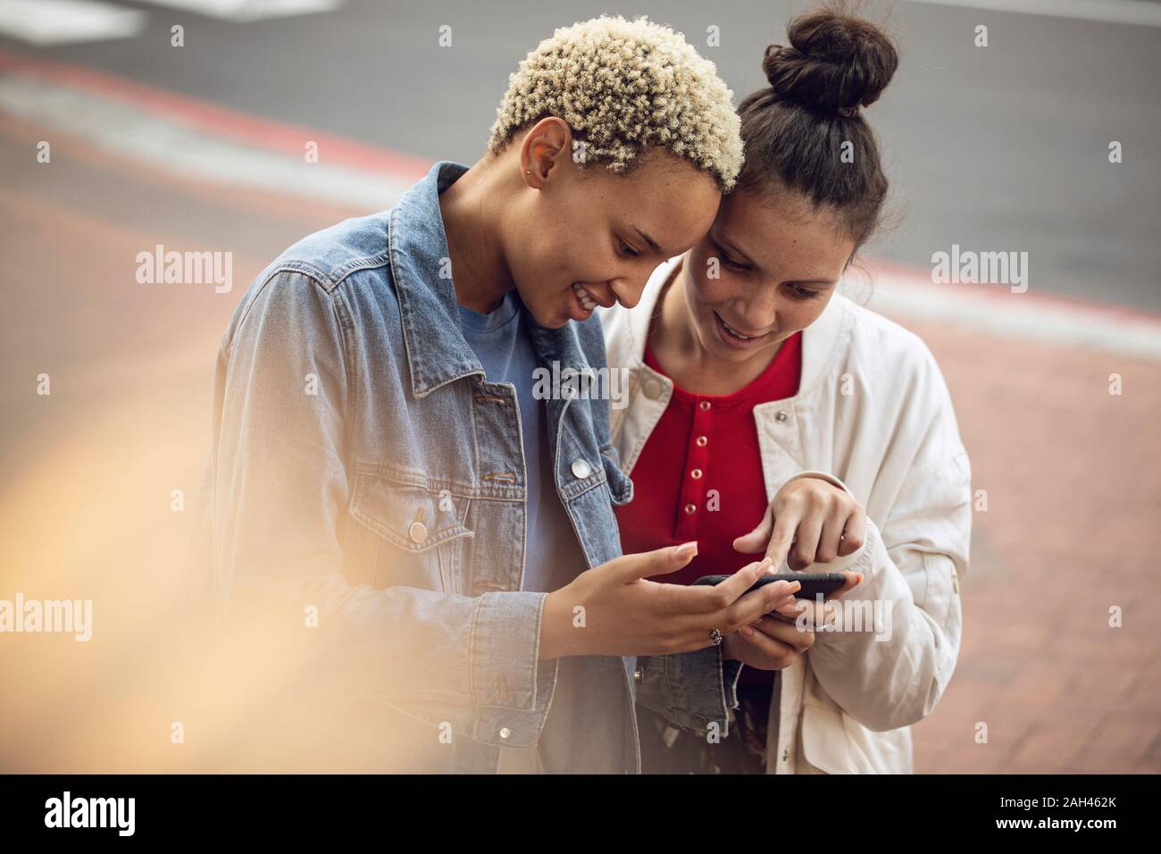 Due giovani donne smartphone il controllo nella città Foto Stock