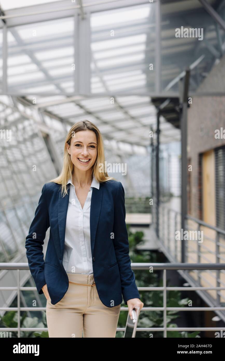 Ritratto di un sorridente giovane imprenditrice in un moderno edificio per uffici Foto Stock