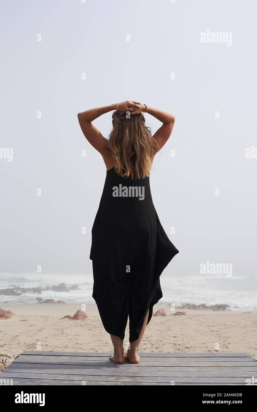Vista posteriore della donna in piedi sull'oceano, Cape Cross, Namibia Foto Stock