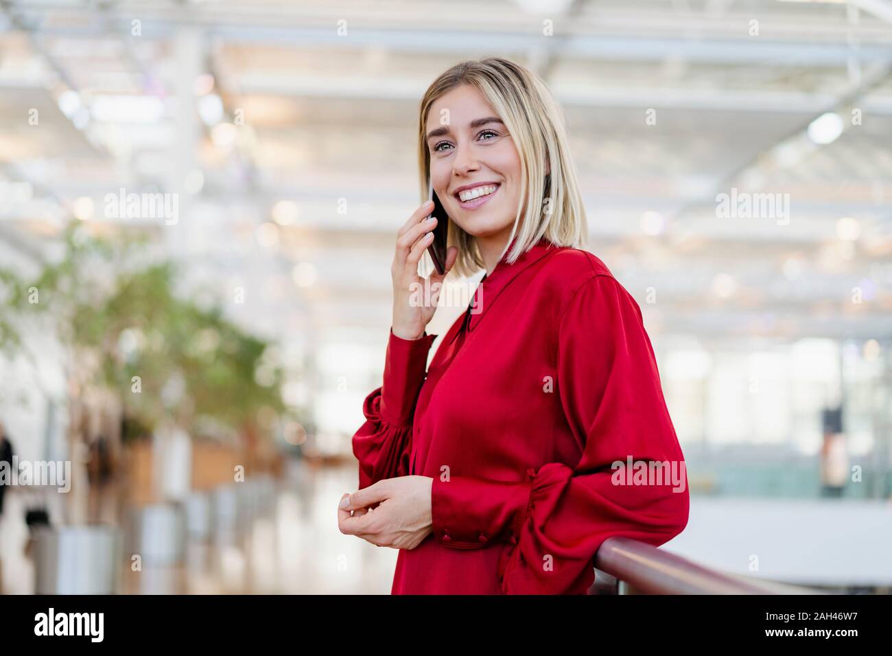 Sorridente giovane imprenditrice al telefono in piedi in una ringhiera Foto Stock