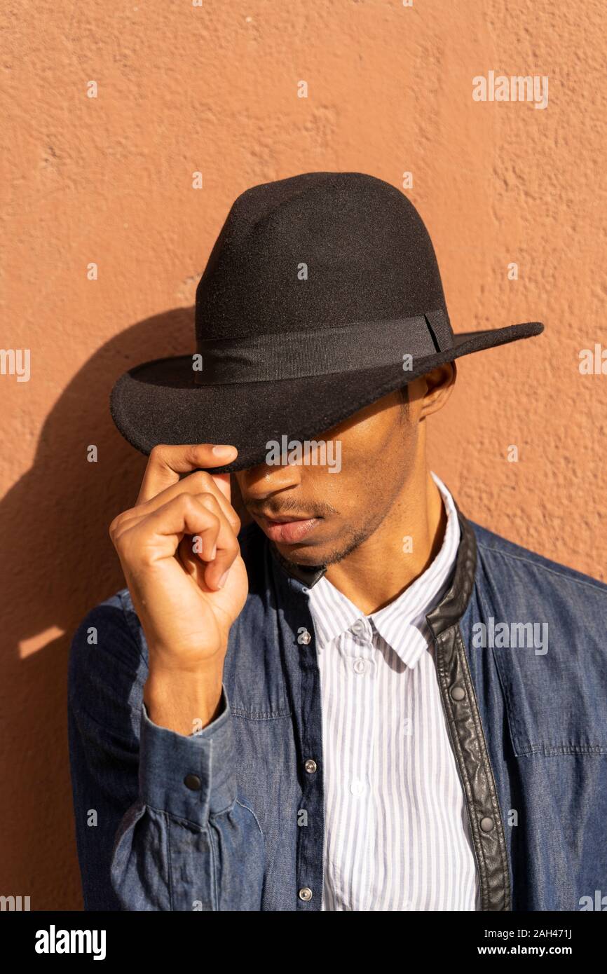 Elegante giovane uomo che indossa un cappello a una parete Foto Stock