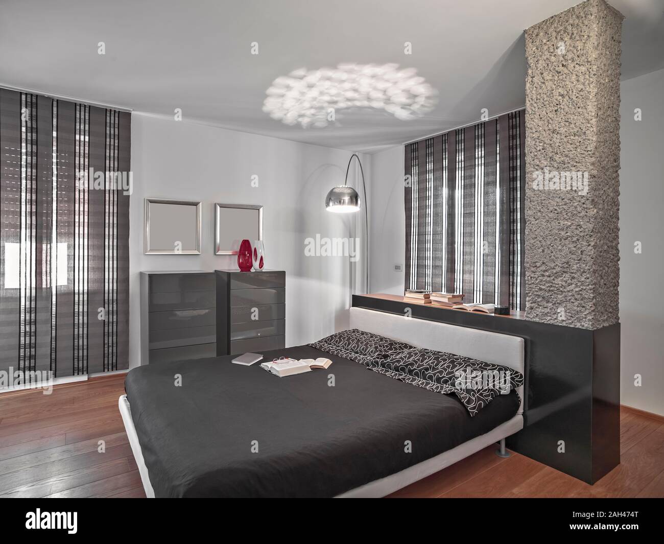 Interior shot di una moderna camera da letto con il letto al centro della stanza il pavimento è in legno Foto Stock
