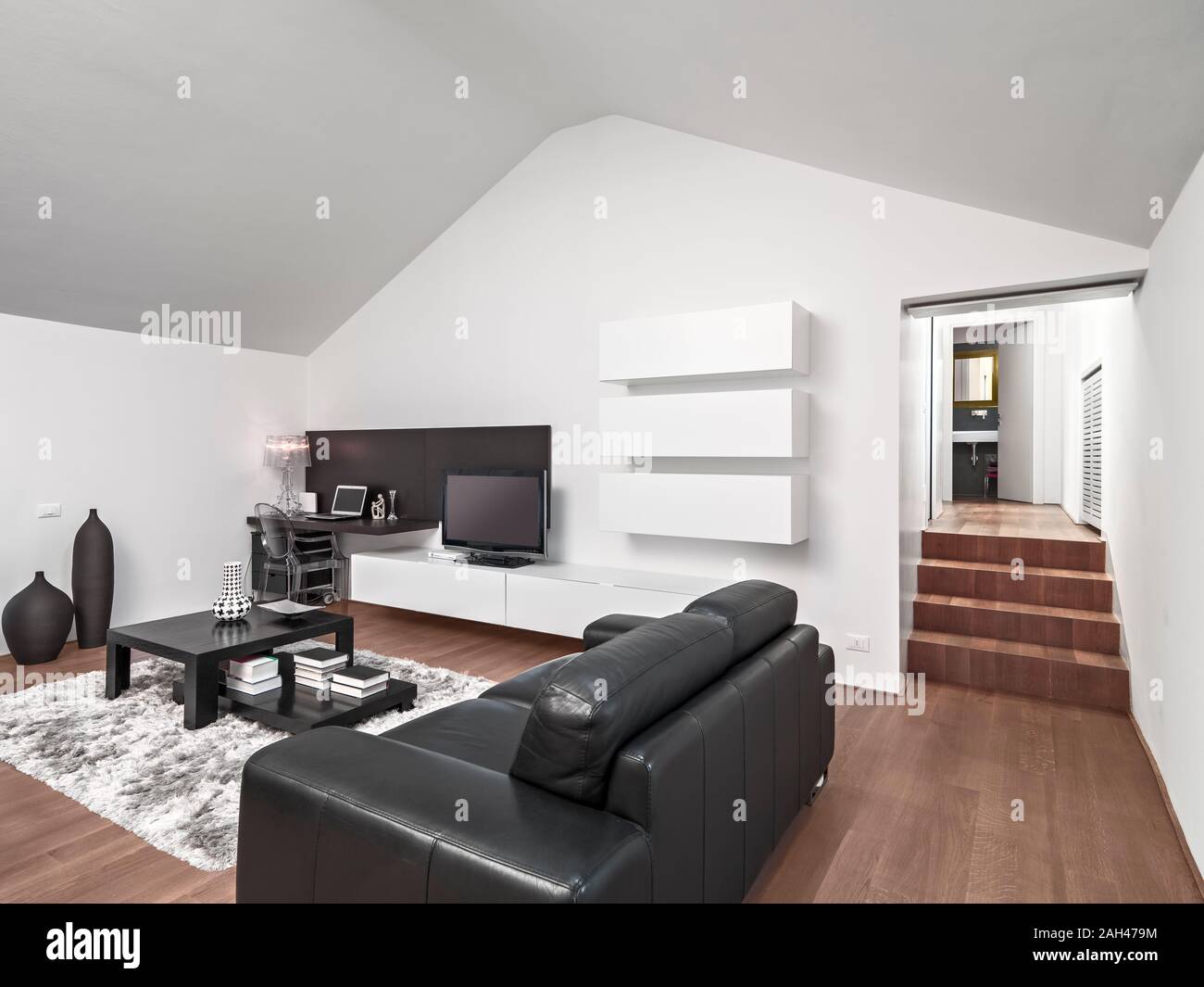 Interior shot di un moderno soggiorno con divano in pelle in soffitta ha il pavimento è realizzato in legno Foto Stock