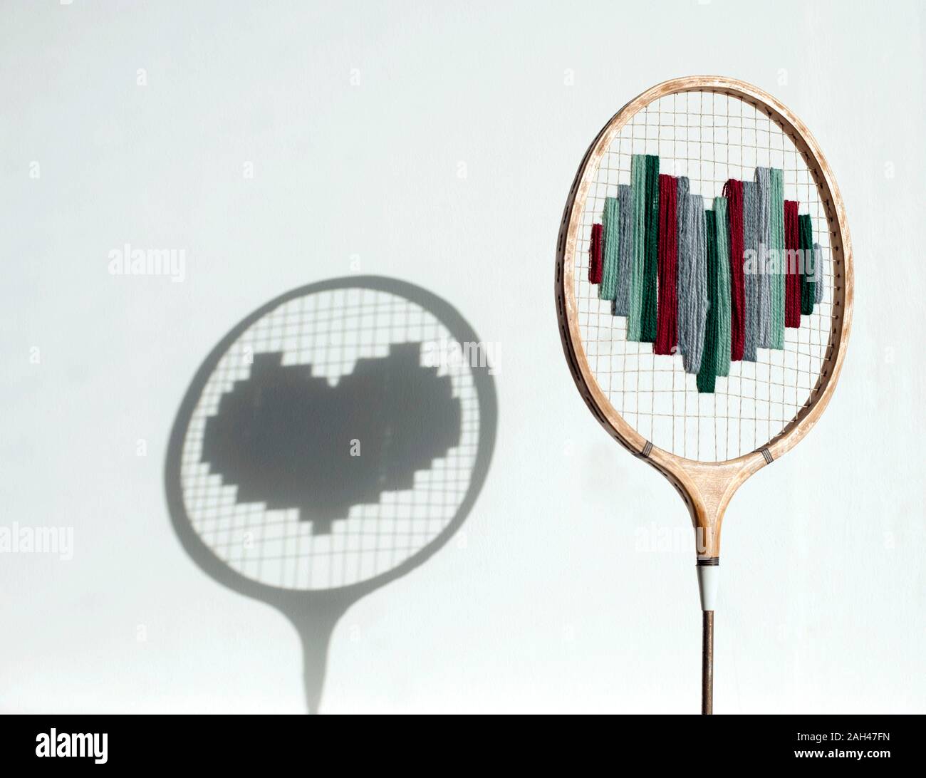 Badminton racchetta con cuore di lana e di ombra sulla parete Foto Stock