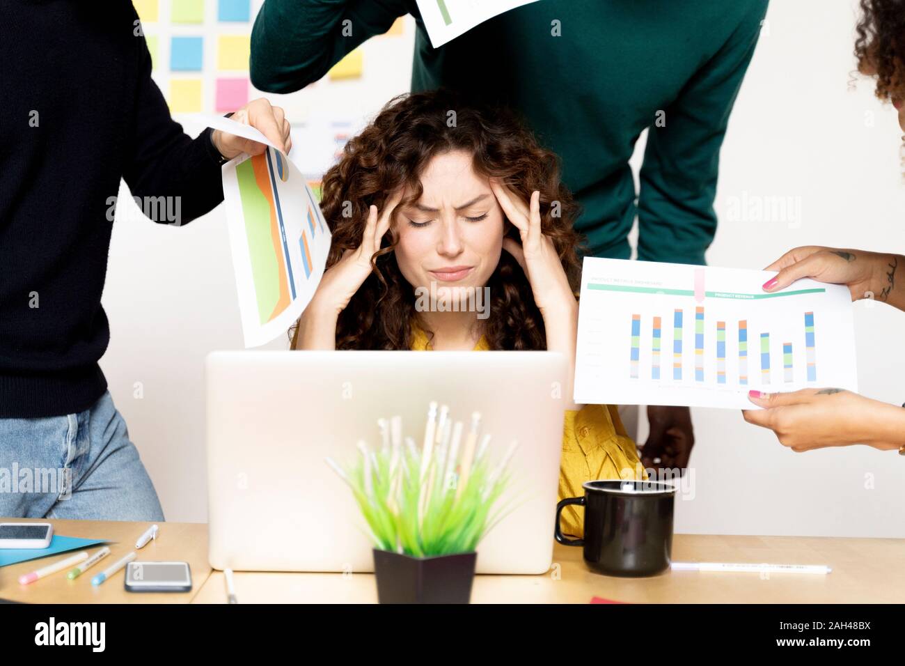 Ha sottolineato la donna posa alla scrivania in ufficio circondato da colleghi Foto Stock