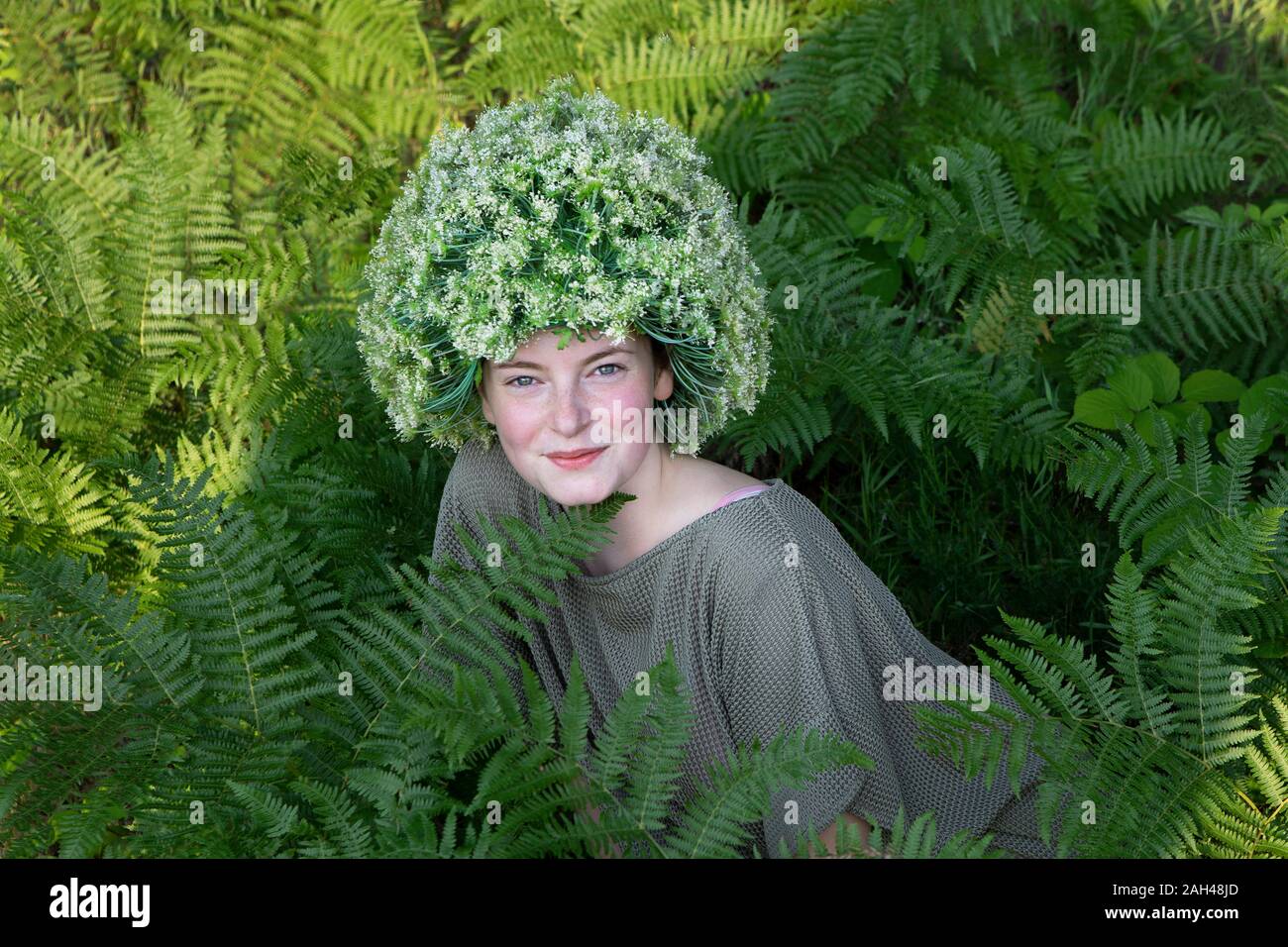 Ritratto di giovane donna tra fern indossando capocchia di fiori Foto Stock