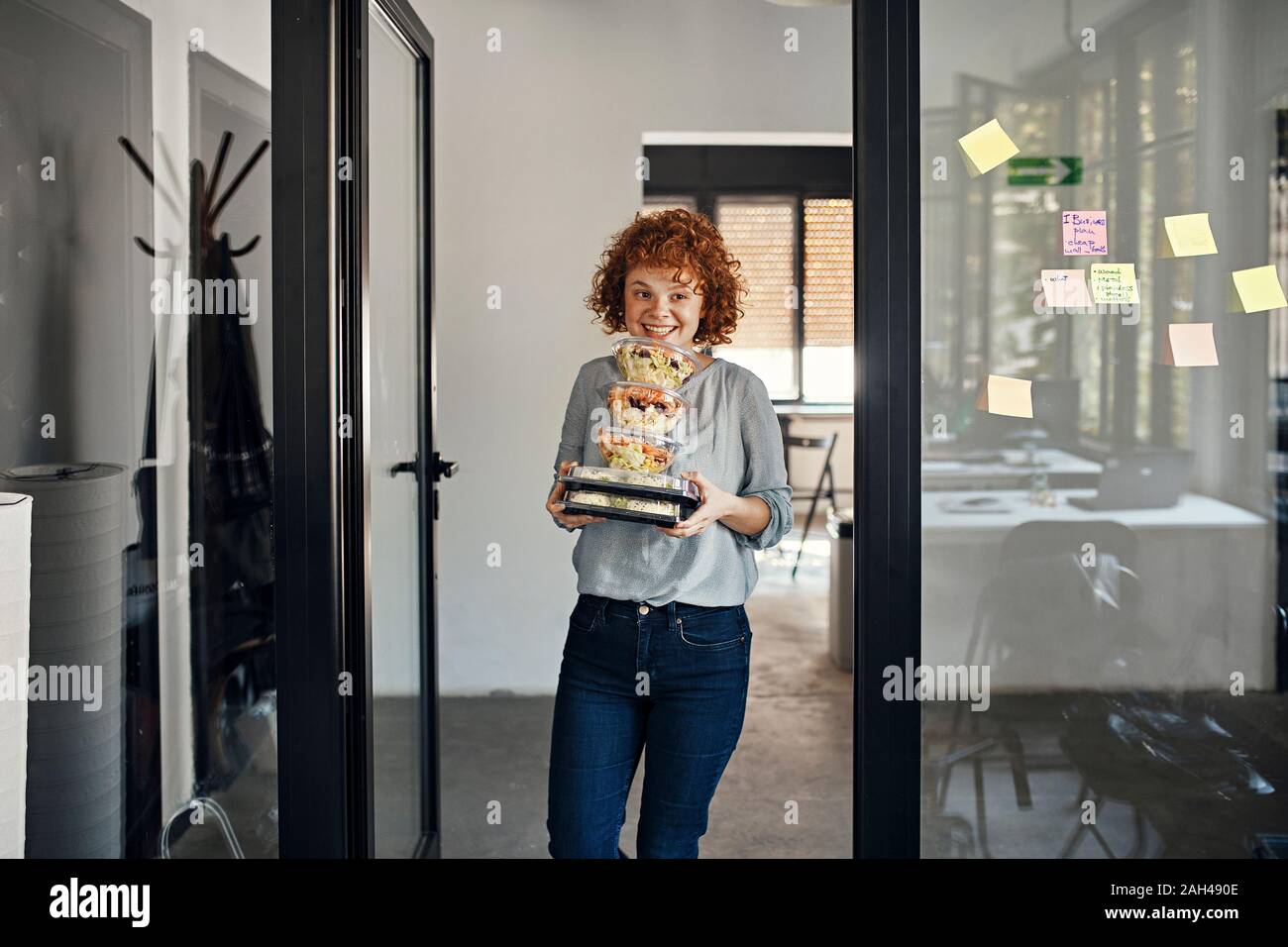 Sorridente imprenditrice che serve cibo da asporto in office Foto Stock
