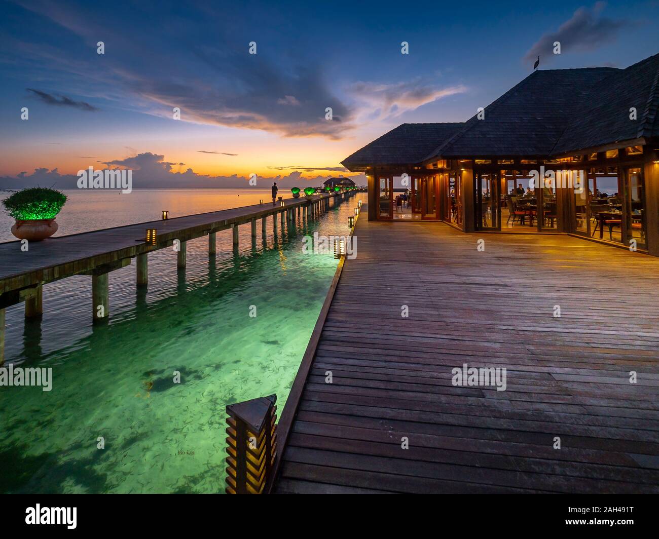 Le Maldive, il molo lungo il ristorante costiere su South Male Atoll al crepuscolo Foto Stock