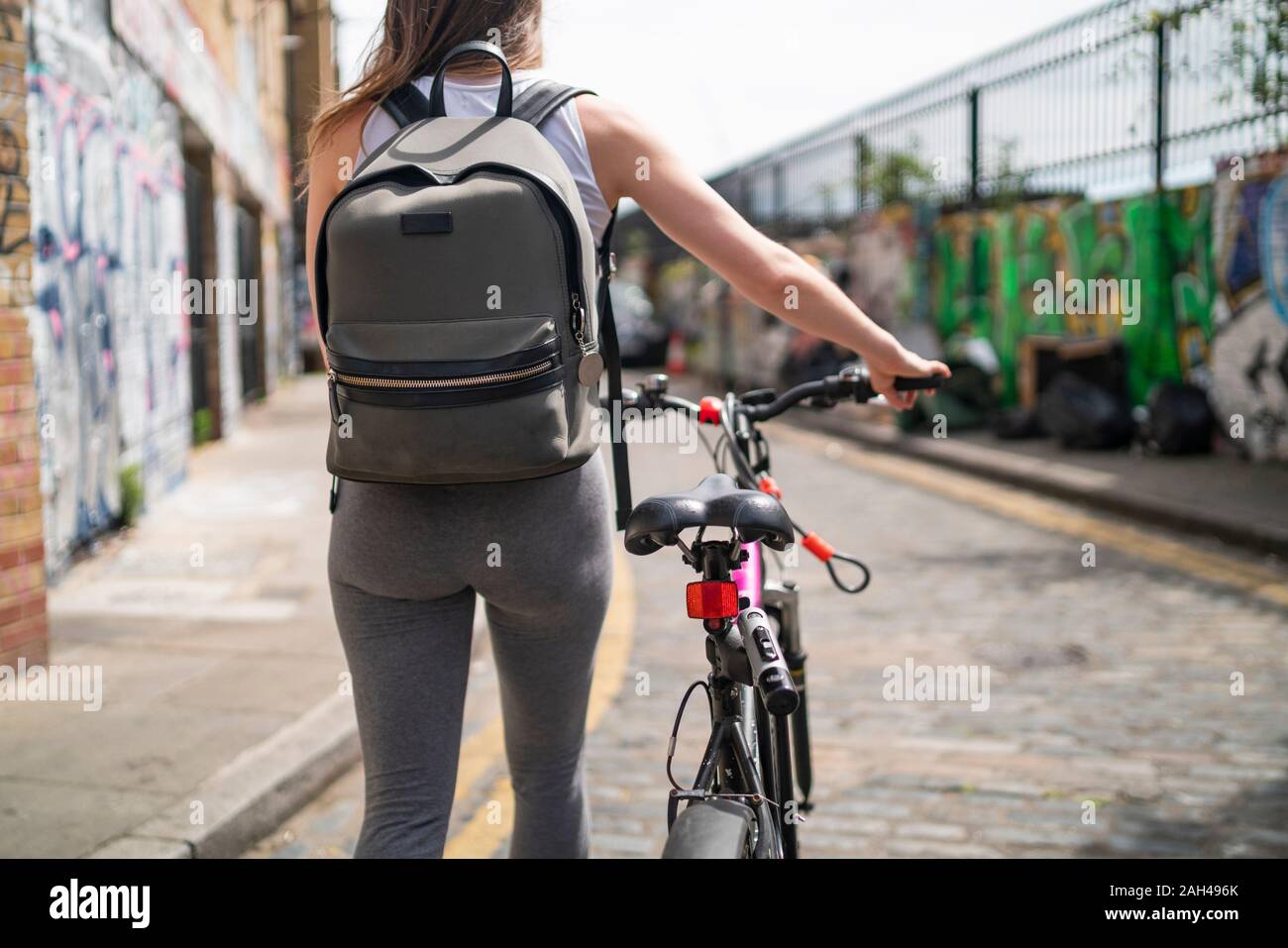 Giovane donna spingendo la bici in città Foto Stock