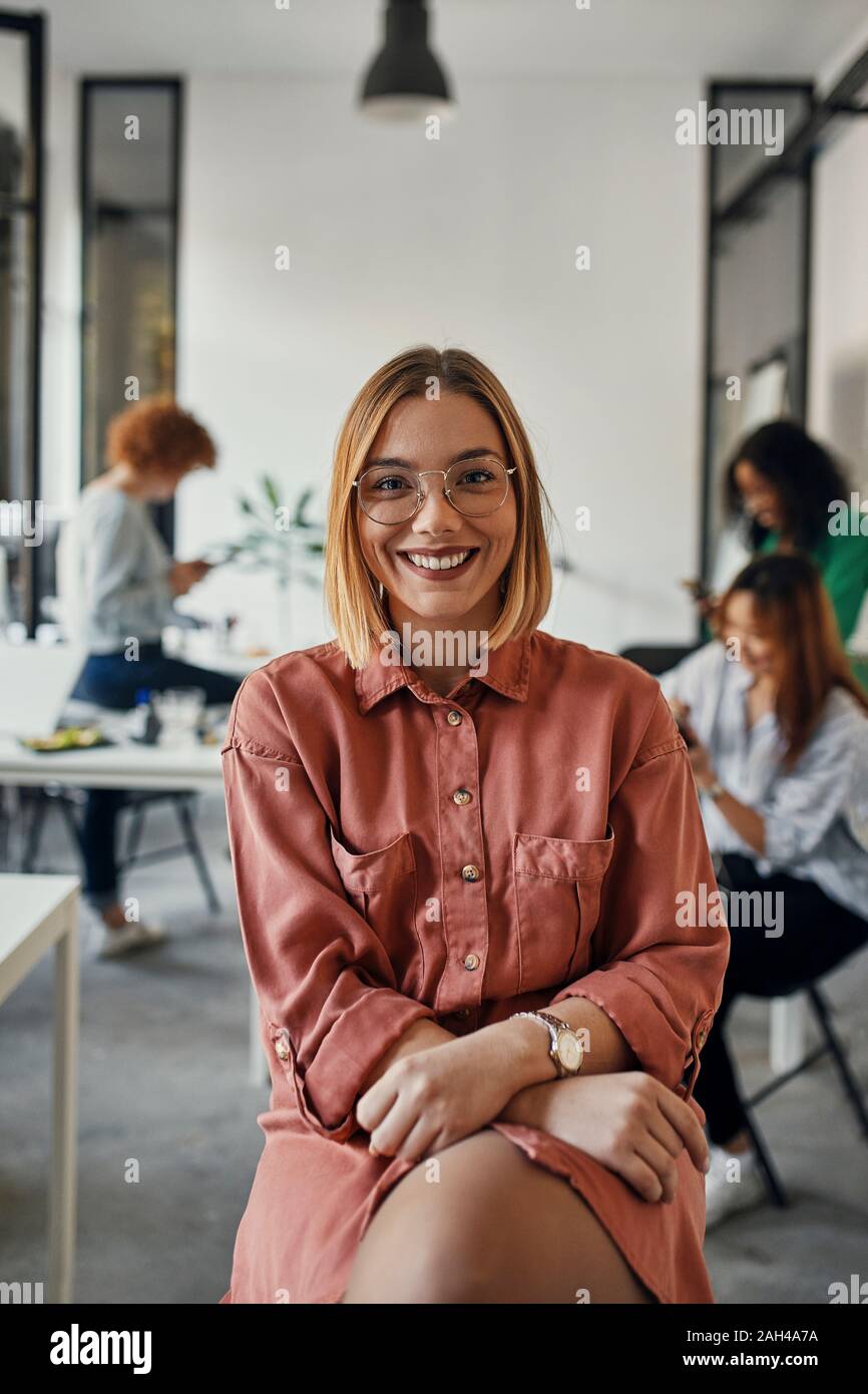Ritratto di un fiducioso imprenditrice in ufficio con i colleghi in background Foto Stock