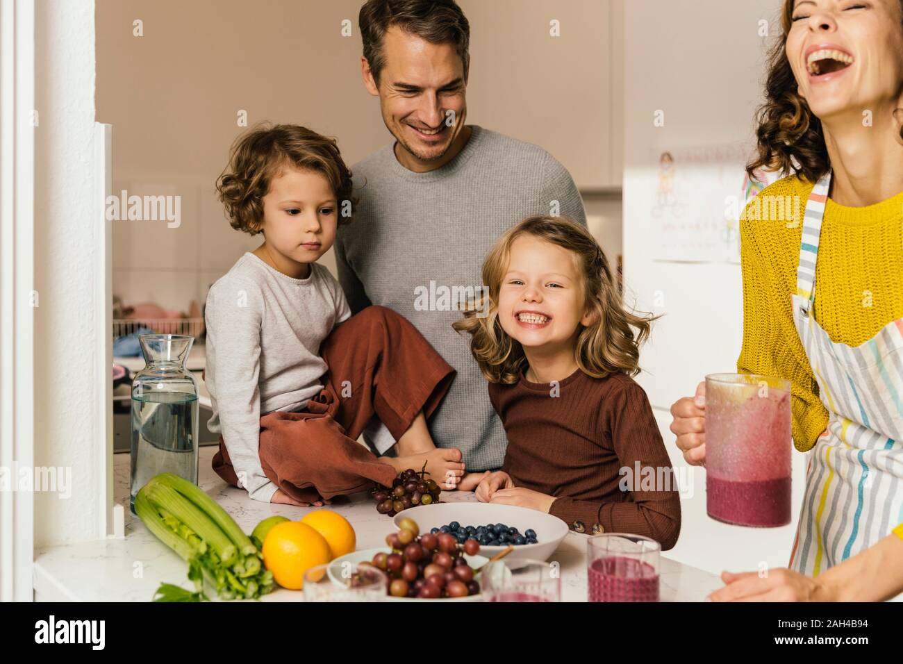 La famiglia felice facendo un smoothie in cucina Foto Stock