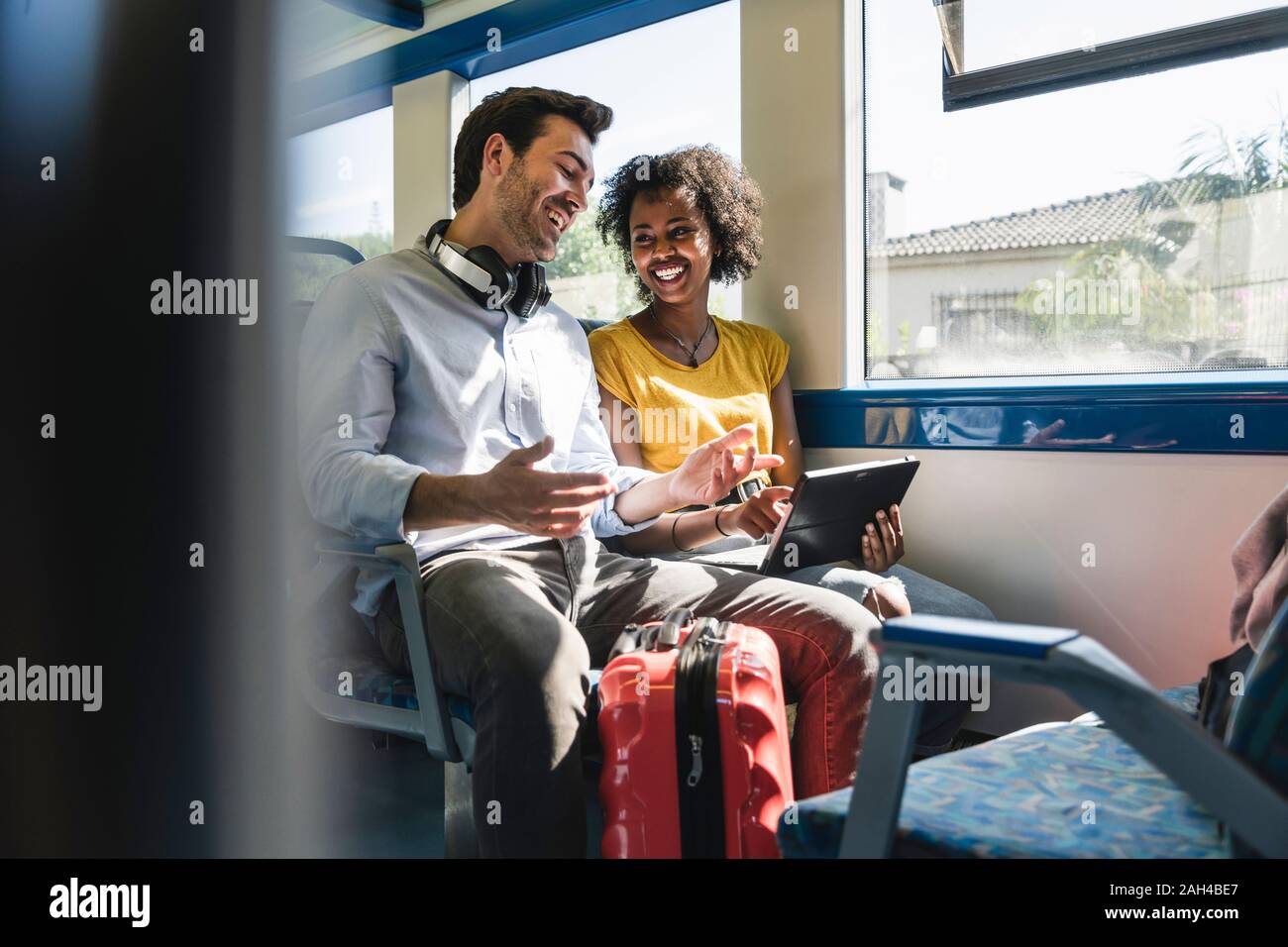 Felice coppia giovane utilizzando compressa in un treno Foto Stock
