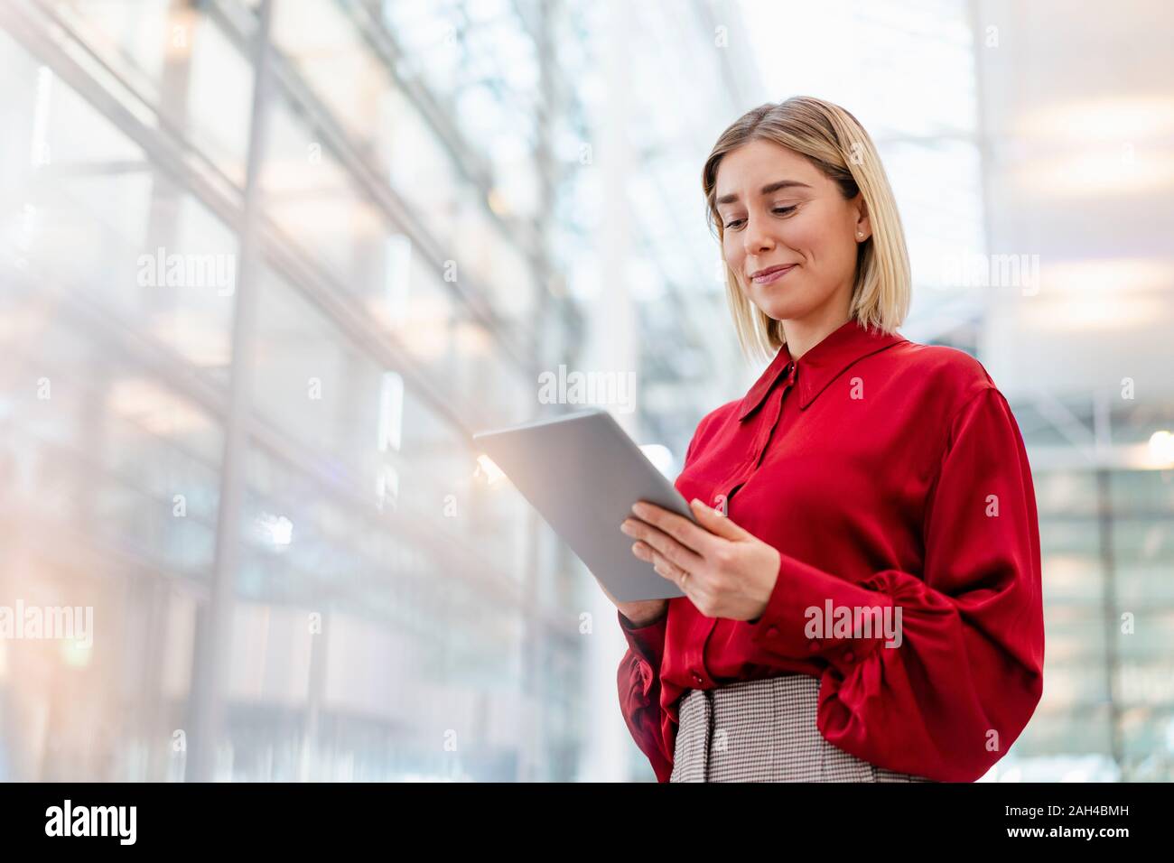Giovane imprenditrice indossando maglietta rossa utilizzando tablet Foto Stock