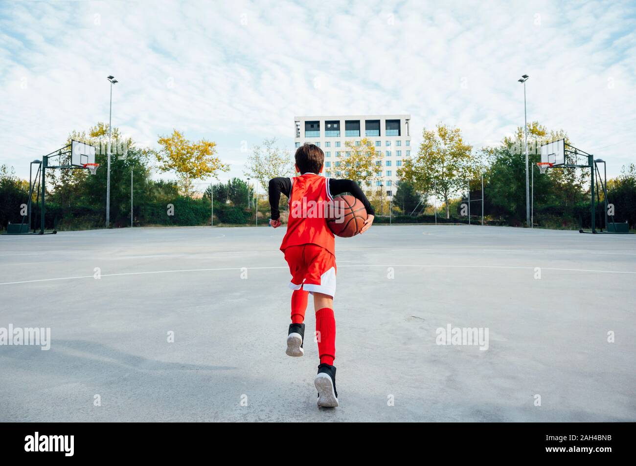 Ragazzo giocare a basket sulla corte esterna Foto Stock