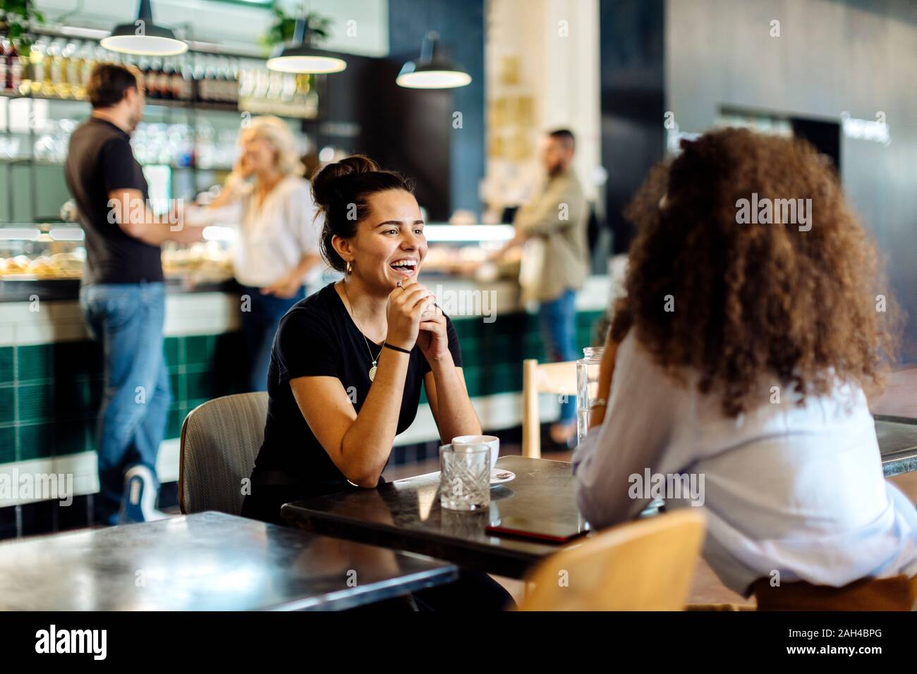 Due amiche incontrare e parlare in un bistro Foto Stock