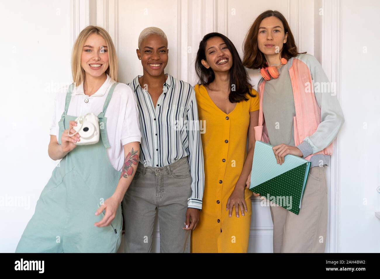 Ritratto di quattro donne sorridente in piedi a fianco a fianco Foto Stock
