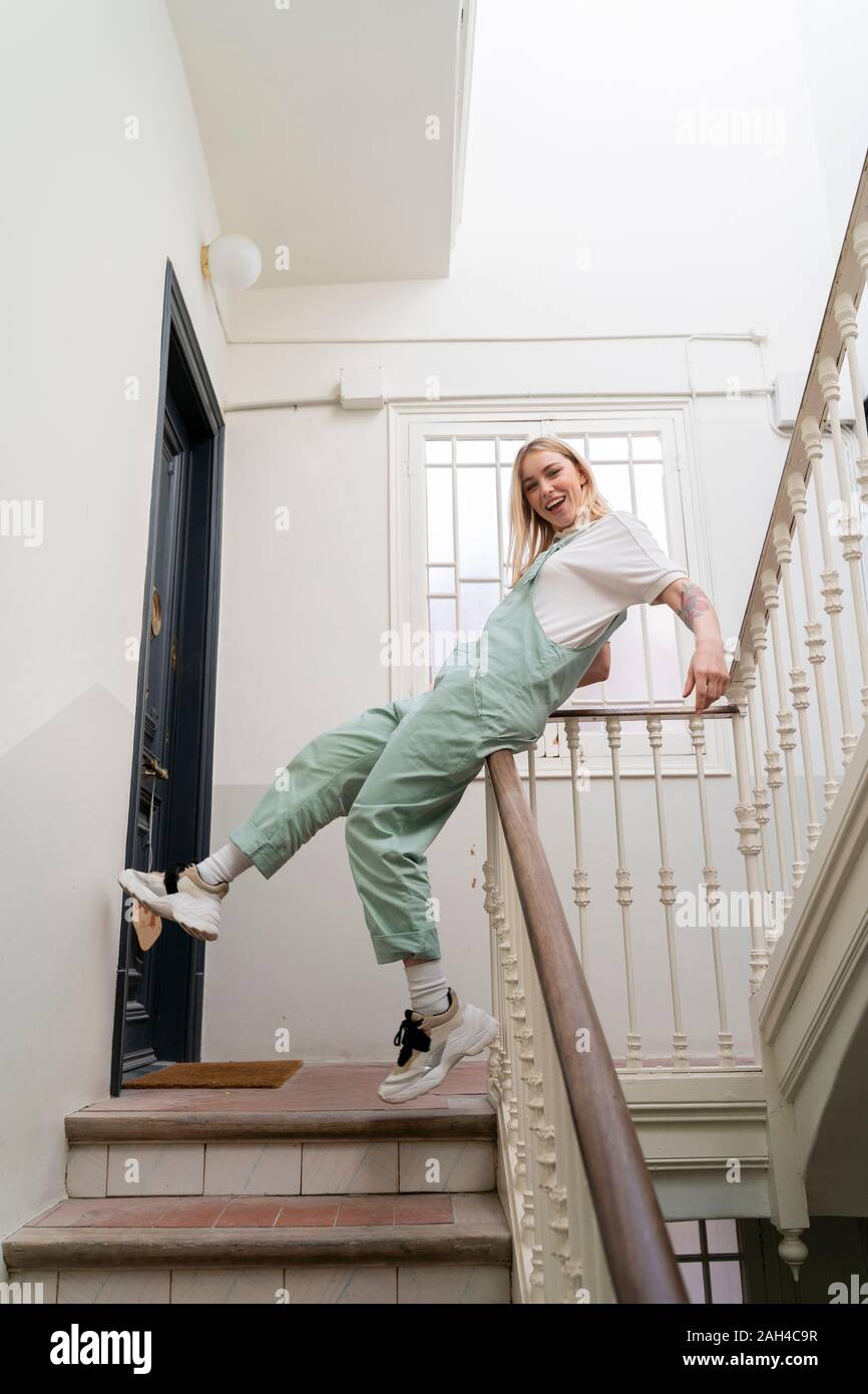 Spensierato giovane donna scorrimento sulla ringhiera in scala Foto Stock