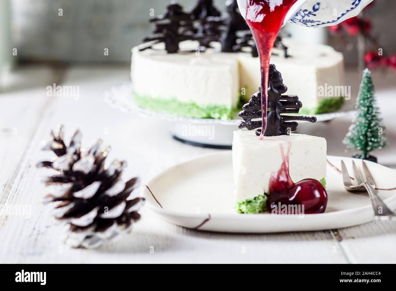 Pezzo di no-bake cheesecake, decorata con cioccolato alberi di Natale sulla piastra calda con salsa alle ciliegie Foto Stock