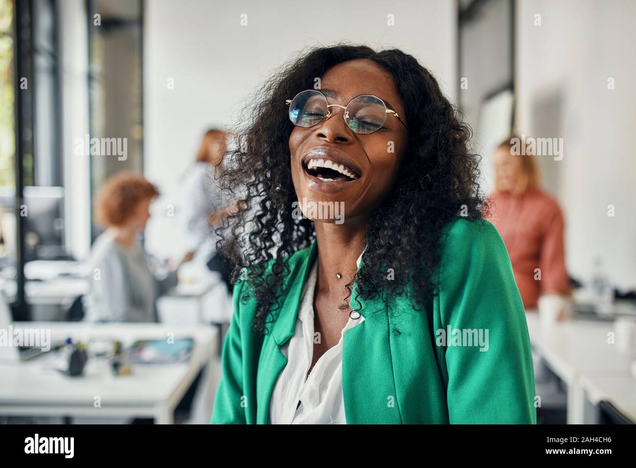 Ritratto di un ridere imprenditrice in ufficio con i colleghi in background Foto Stock