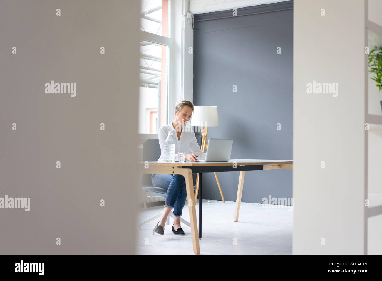 Giovane imprenditrice utilizzando laptop alla scrivania in ufficio Foto Stock