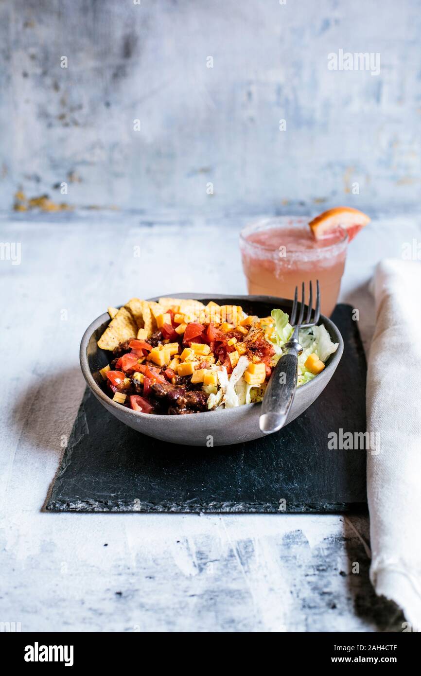 Ciotola di nachos con, chili con carne, riso, lattuga, formaggio, pomodori  e bicchiere rinfrescante di paloma cocktail Foto stock - Alamy