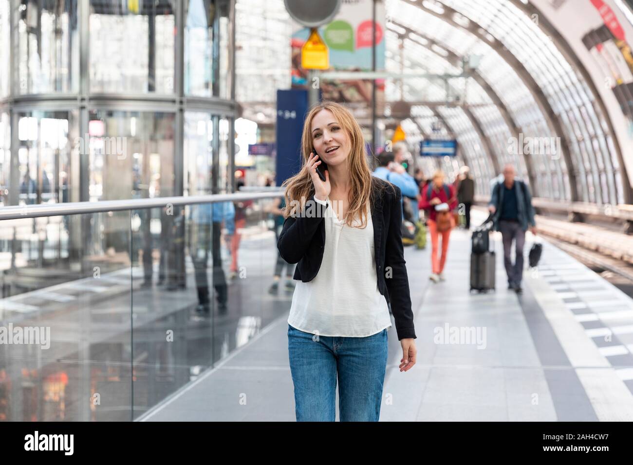Donna al telefono sulla piattaforma della stazione, Berlino, Germania Foto Stock