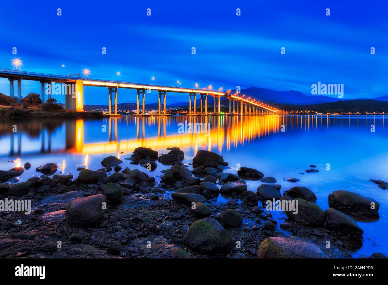 Tasman ponte attraverso il fiume Derwent presso sunrise durante ore blu luminoso con luci di illuminazione in vista di Hobart sul lungomare della citta'. Foto Stock