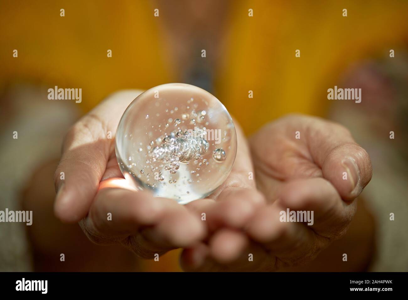 Chiudere fino alle mani di un lettore psichica in possesso di una sfera di cristallo con profondità di campo Foto Stock