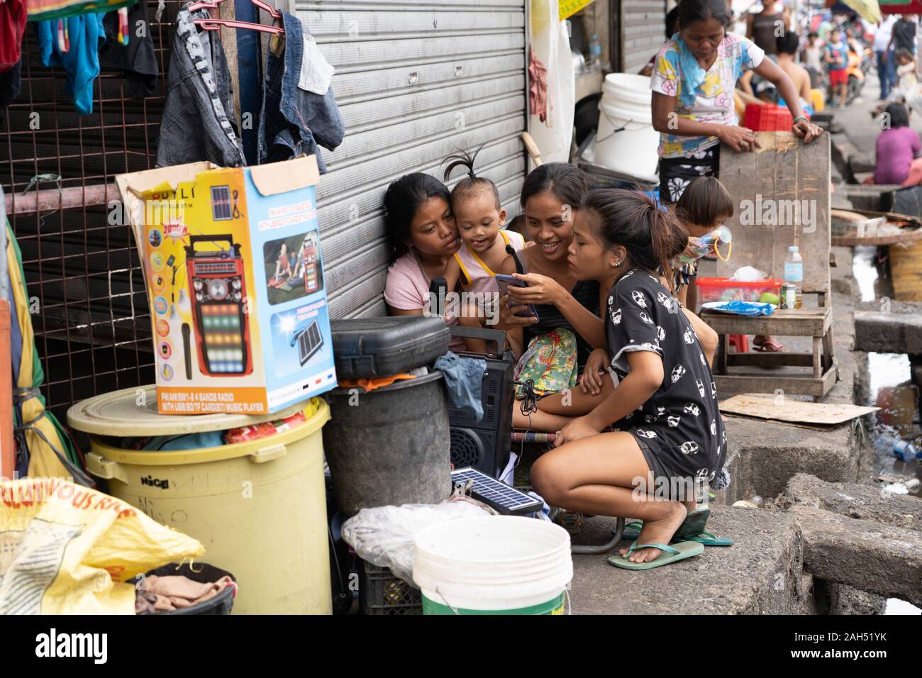 Le ragazze la scelta di brani su un telefono cellulare collegato ad un karaoke entro una zona povera di Cebu City, Filippine Foto Stock