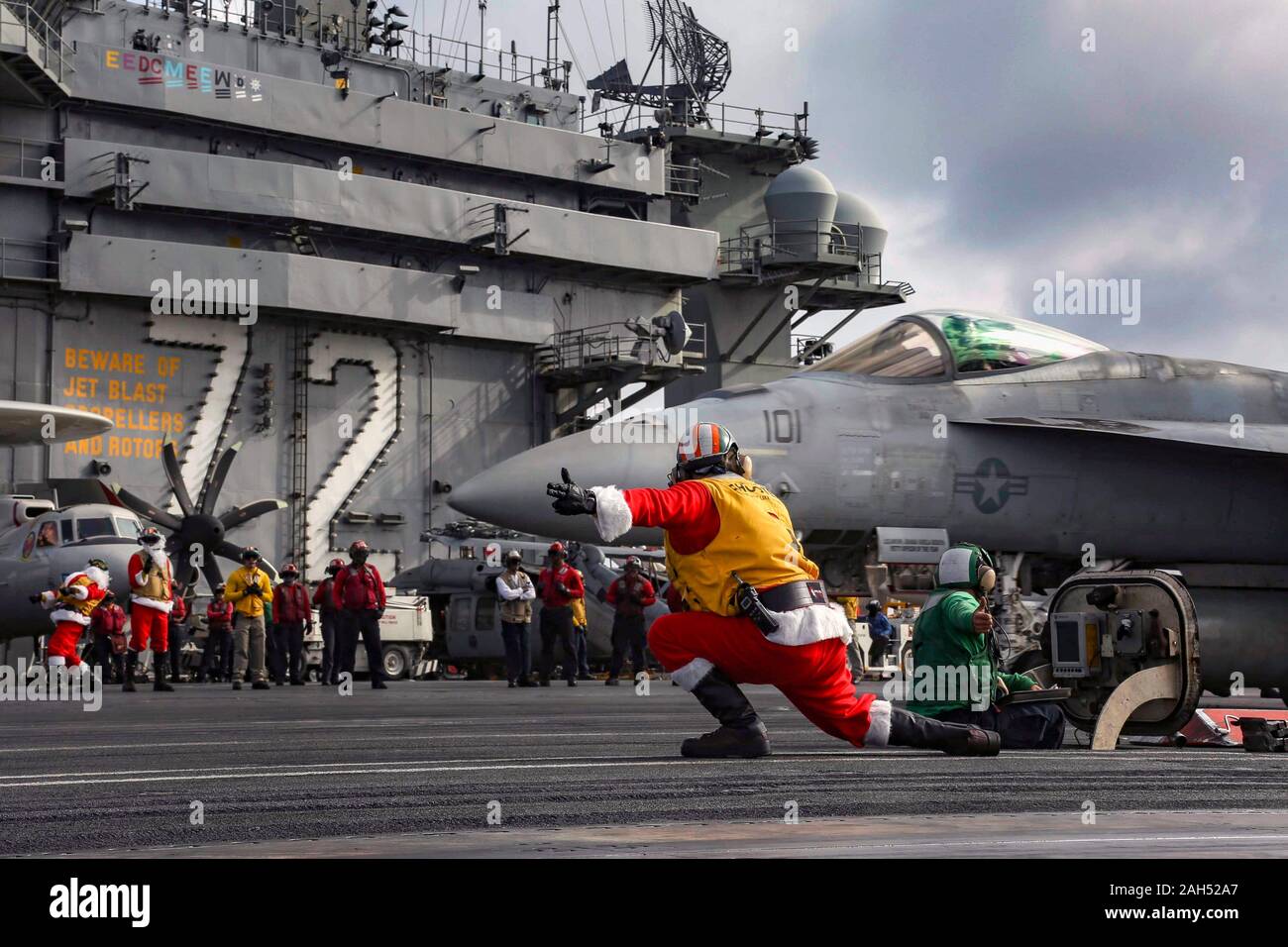 USS Abraham Lincoln, Stati Uniti. 24 dicembre, 2019. Un U.S. Navy sailor vestiti da Babbo Natale dirige il lancio di un'F/A-18E Super Hornet fighter aircraft sul ponte di volo dell'Nimitz-class portaerei USS Abraham Lincoln durante le operazioni per la Vigilia di Natale 24 dicembre 2019 nel Mare della Cina del Sud. Credito: Geremia Bartelt/STATI UNITI Navy/Alamy Live News Foto Stock