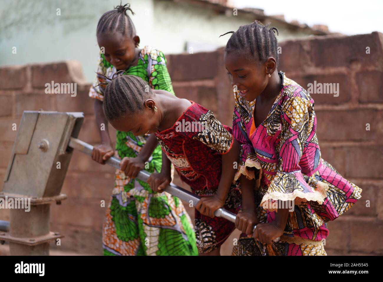 Tre Piccole Ragazze Africane Sorridenti Busy Acquaforte Acqua Alla Pompa Di Villaggio Foto Stock