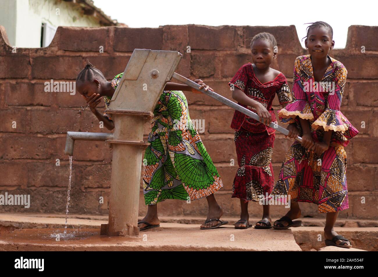 Tre Ragazze Africane Poco Desiderose Che Provano Fuori La Loro Stazione Di Pompaggio Di Acqua Di Villaggio Foto Stock