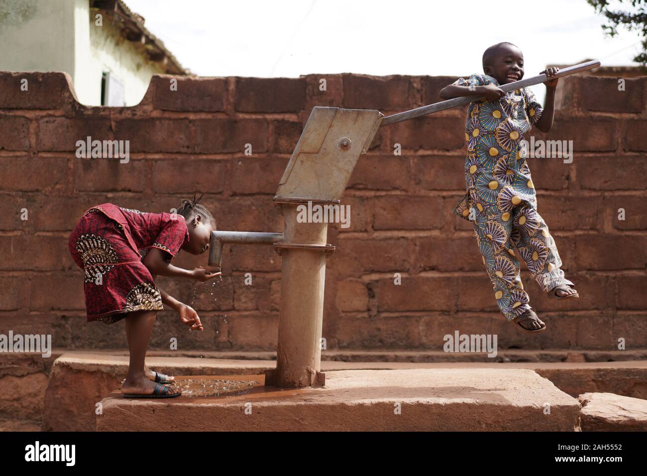 Bambini Africani Giocando Al Pompa Dell'Acqua Del Villaggio Foto Stock