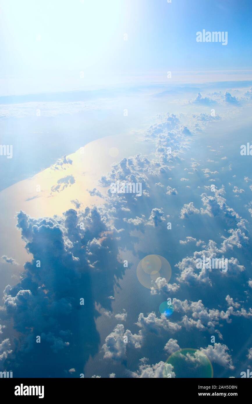Bella vista da finestra di aereo sopra le nuvole e la superficie del mare. Panorama naturale con le nuvole. Nuvole bianche si muove al di sopra della superficie dell'acqua di mare. Foto Stock