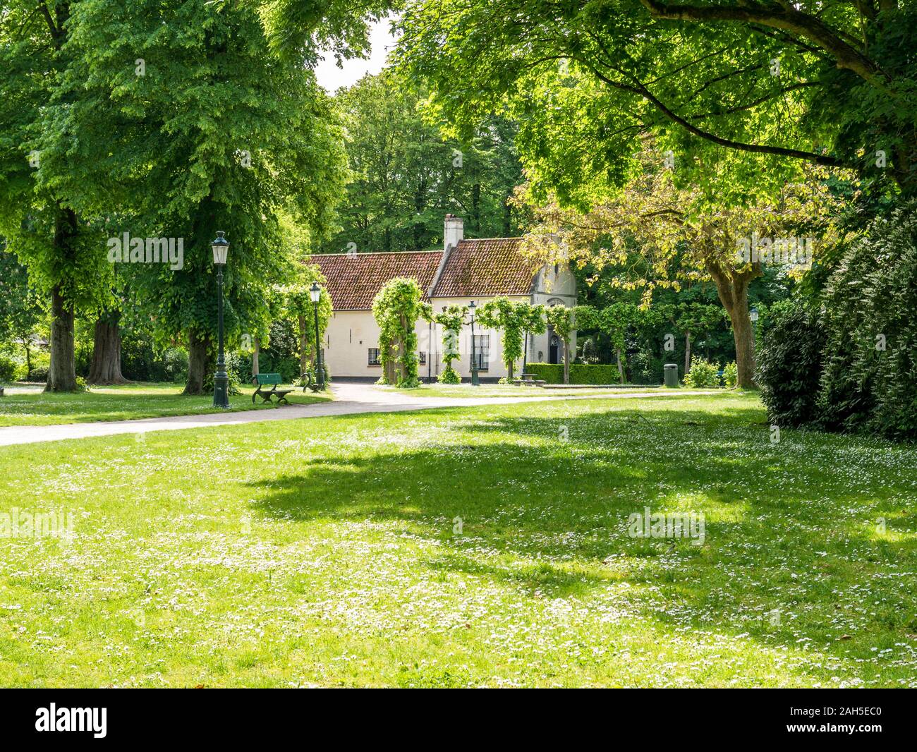 Prato verde, la casa e gli alberi in Minnewaterpark in Bruges, Fiandre Occidentali, Belgio Foto Stock