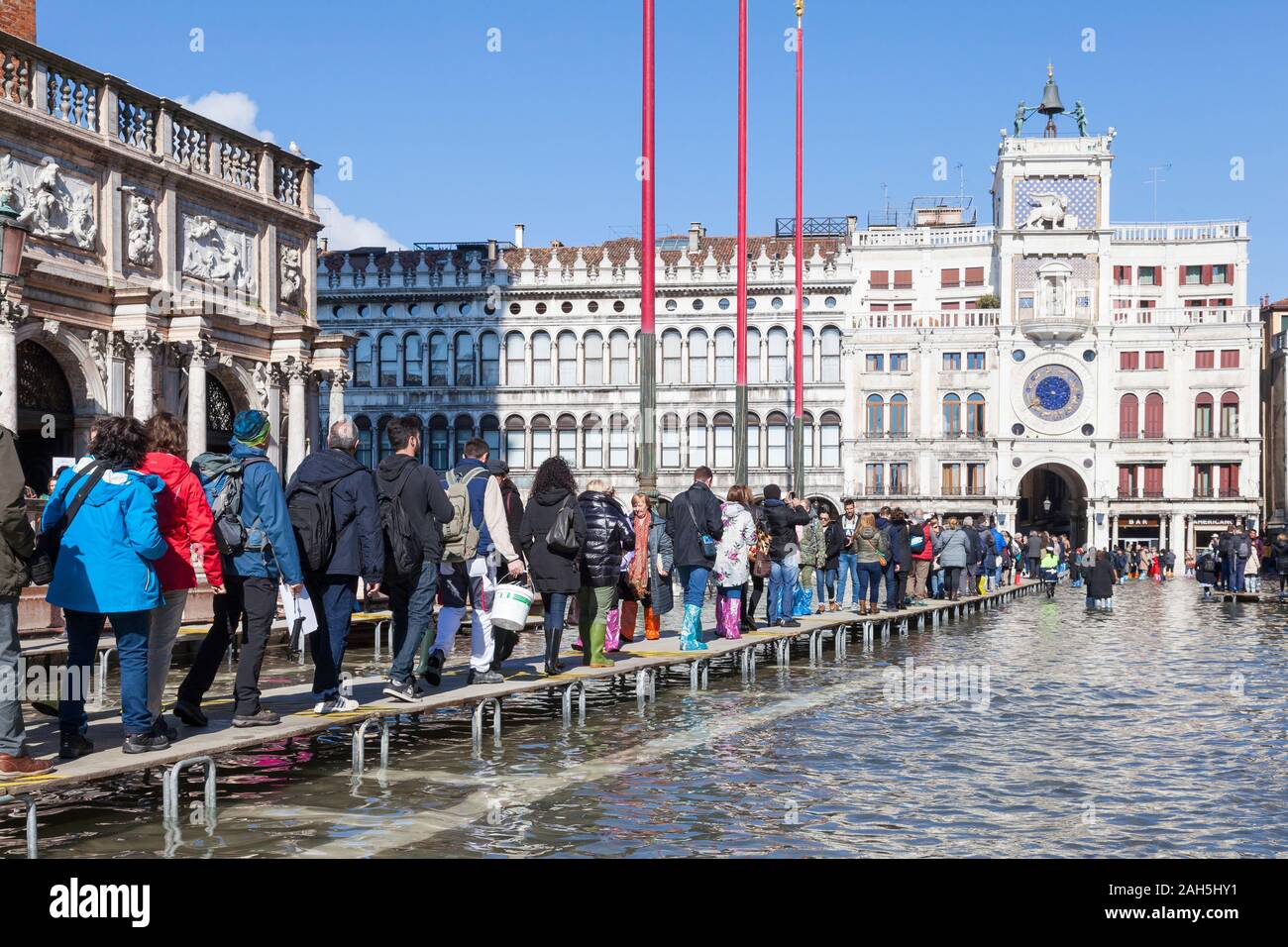 Acqua Alta inondazioni durante l estrema alta marea Piazza San Marco, Venezia, Italia, lungo la linea di turisti su passeroles o elevati passaggi pedonali che conducono a Clo Foto Stock