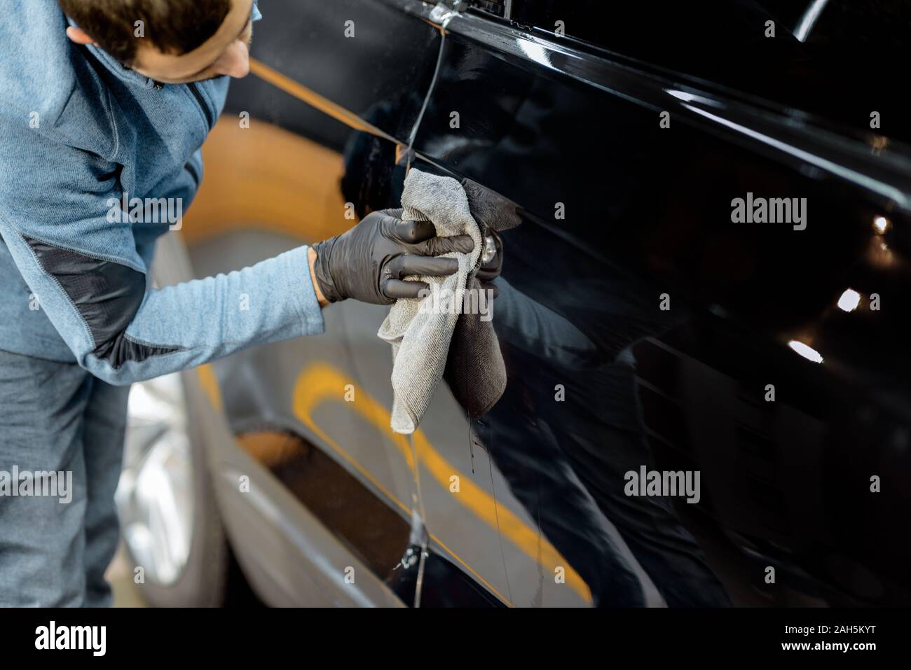 Grippaggio del lavoratore di protezione pellicola trasparente su un corpo vettura al posto della maniglia della porta, vista da vicino Foto Stock