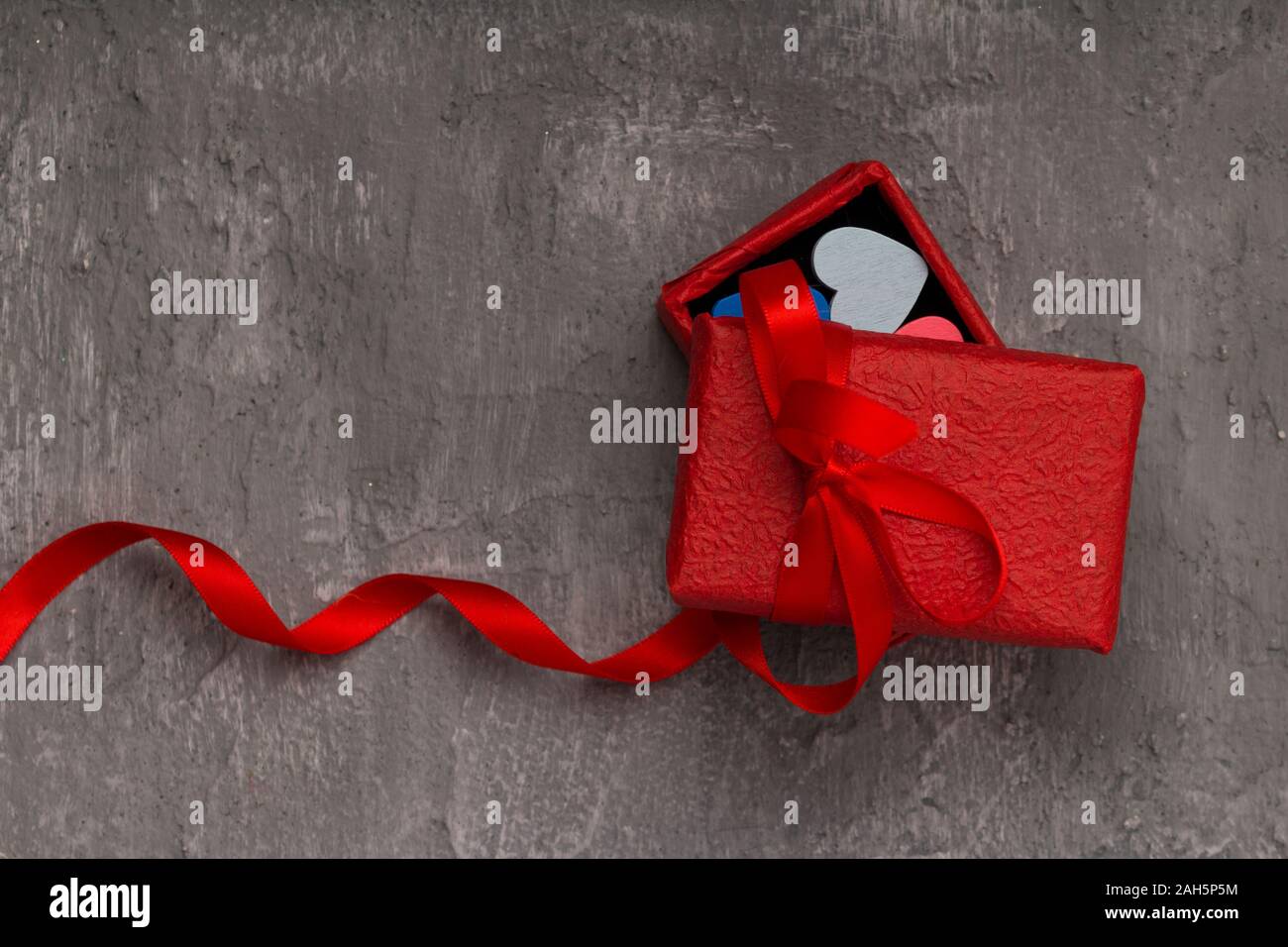 Il giorno di San Valentino sfondo con cuori e una confezione regalo rossa sulla scheda di calcestruzzo . close up , spazio di copia Foto Stock
